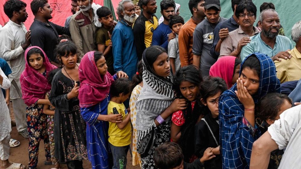 Vítimas afetadas pelas enchentes fazem fila para receber ajuda alimentar em um acampamento improvisado construído em um terreno elevado em uma área inundada nos arredores de Lahore, em 1º de setembro de 2025. Quase meio milhão de pessoas foram deslocadas pelas enchentes no leste do Paquistão após dias de fortes chuvas que causaram o transbordamento dos rios, disseram autoridades humanitárias em 30 de agosto, enquanto realizavam uma grande operação de resgate. (Foto de Arif ALI / AFP)