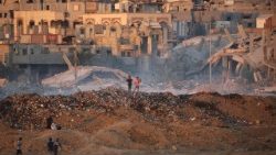  Palestinian children walk over a mound of dirt and trash at the Bureji displaced persons camp in the central Gaza Strip.