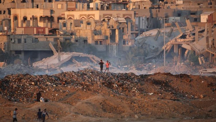  Palestinian children walk over a mound of dirt and trash at the Bureji displaced persons camp in the central Gaza Strip.
