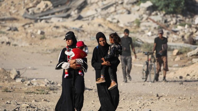Palestinian women carrying their children make their way to Gaza City