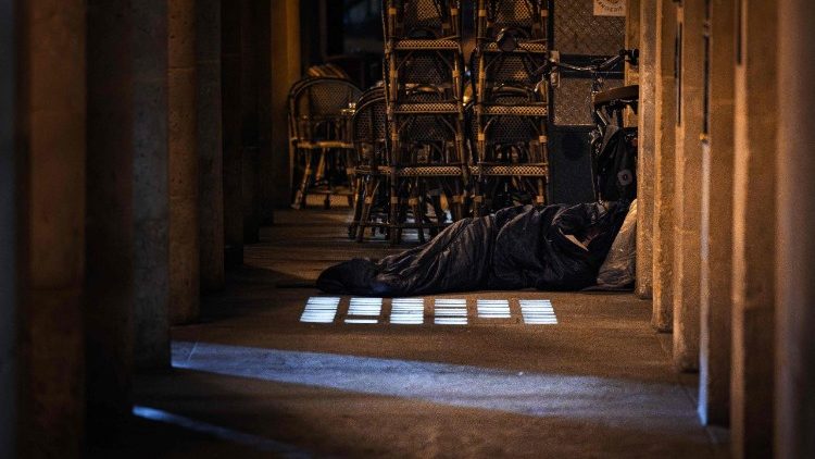 A man sleeps in a sleeping bag next to a cafe on 15 October 2025