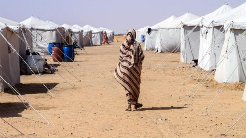 A Sudanese woman who fled El-Fasher walks past tents at a camp for displaced people 