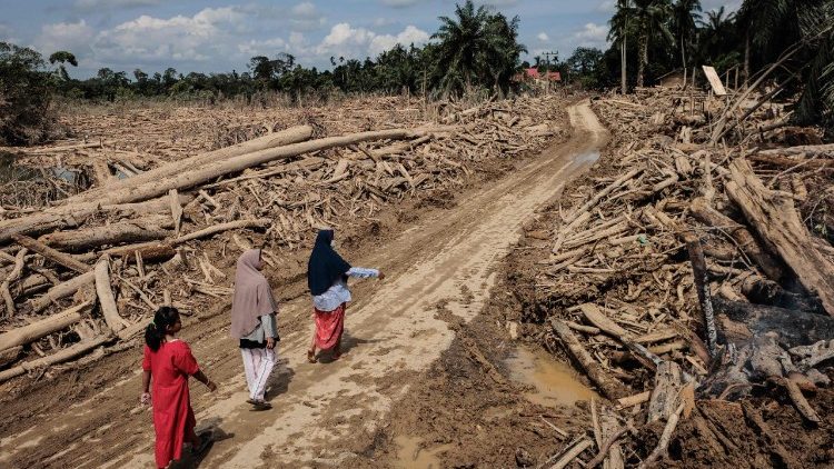 उतरी सुमात्रा के बाढ़ से प्रभावित क्षेत्र में चलती हुई महिलायें