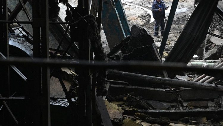 Funcion&aacute;rios est&atilde;o ao lado do pr&eacute;dio de uma usina da fornecedora de energia ucraniana DTEK, que foi severamente danificada durante ataques a&eacute;reos, em um local n&atilde;o divulgado em 10 de dezembro de 2025, em meio &agrave; invas&atilde;o russa da Ucr&acirc;nia. (Foto de YURIY DYACHYSHYN / AFP)