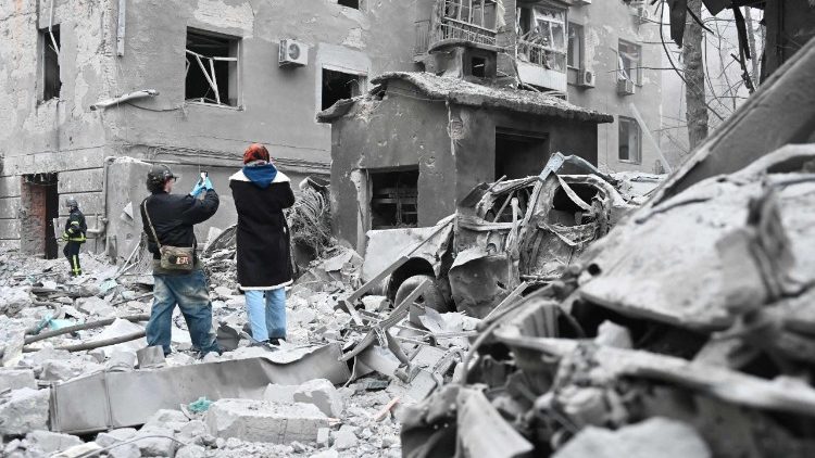 Moradores locais observam pr&eacute;dios residenciais danificados ap&oacute;s um ataque a&eacute;reo russo em Kharkiv, em 2 de janeiro de 2026, durante a invas&atilde;o russa da Ucr&acirc;nia. (Foto de SERGEY BOBOK / AFP)