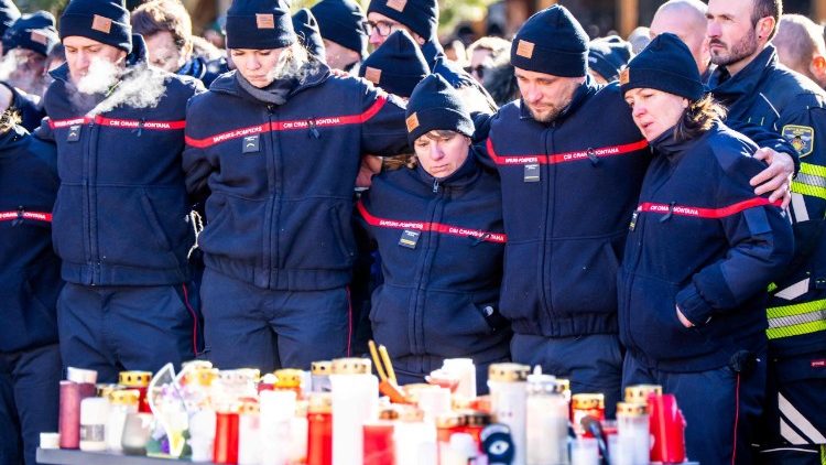 Bombeiros do município de Crans-Montana reagem enquanto se reúnem em torno de um memorial improvisado para prestar suas homenagens, depositando flores, velas e mensagens perto do bar Constellation, em 4 de janeiro de 2026, em Crans-Montana, em memória das vítimas do incêndio que devastou o local na luxuosa estação de esqui alpina na véspera de Ano Novo. (Foto de MAXIME SCHMID / AFP)
