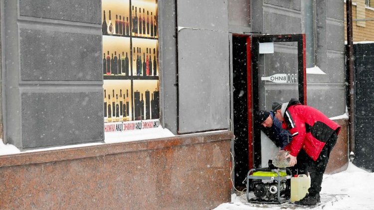 Funcion&aacute;rios reabastecem um gerador de energia do lado de fora de uma loja durante o apag&atilde;o provocado por ataques de drones e m&iacute;sseis russos em Kiev, em 9 de janeiro de 2026, em meio &agrave; invas&atilde;o russa da Ucr&acirc;nia. Os ataques russos cortaram o aquecimento em metade da capital ucraniana na sexta-feira, levando o prefeito a fazer um apelo excepcional para que os moradores deixassem temporariamente a cidade, com temperaturas de -8&deg;C e previs&atilde;o de queda ainda maior. (Foto de Sergei SUPINSKY / AFP)