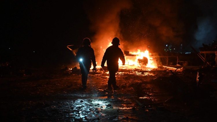 Bombeiros ucranianos trabalham no local de um terminal da empresa postal Nova Poshta, gravemente danificado ap&oacute;s um ataque a&eacute;reo em uma vila nos arredores de Kharkiv, em 13 de janeiro de 2026, em meio &agrave; invas&atilde;o russa da Ucr&acirc;nia. Um ataque russo &agrave; cidade de Kharkiv, no nordeste da Ucr&acirc;nia, matou quatro pessoas e feriu v&aacute;rias outras, disse o governador regional em 13 de janeiro de 2026. (Foto de SERGEY BOBOK / AFP)