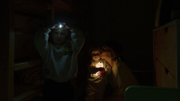 A moradora local Kateryna passa um tempo com seus dois filhos durante um apag&atilde;o no apartamento da fam&iacute;lia em Kiev, em 13 de janeiro de 2026, em meio &agrave; invas&atilde;o russa da Ucr&acirc;nia. (Foto de Andrew Kravchenko / AFP)