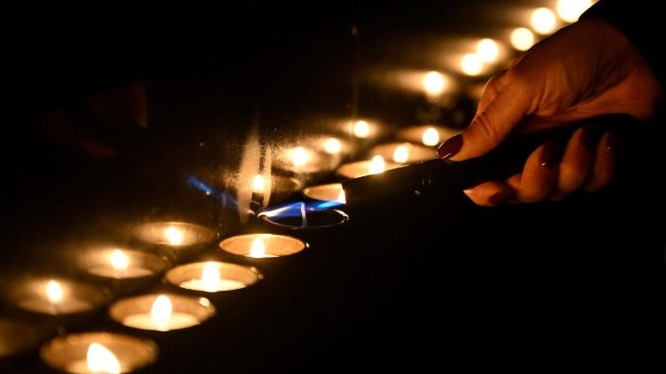 A participant lights candles during a ceremony marking International Holocaust Remembrance Day