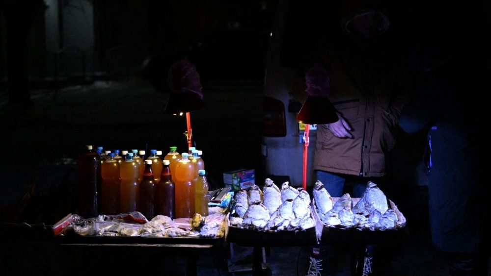 Um morador local vende comida em uma rua durante um apagão em Kiev, em 28 de janeiro de 2026, em meio à invasão russa da Ucrânia. A Rússia intensificou neste mês seus ataques contra a infraestrutura de energia e aquecimento da Ucrânia, mergulhando os moradores de Kiev na escuridão e no frio, com temperaturas chegando a -20°C. (Foto de Sergei Gapon / AFP)