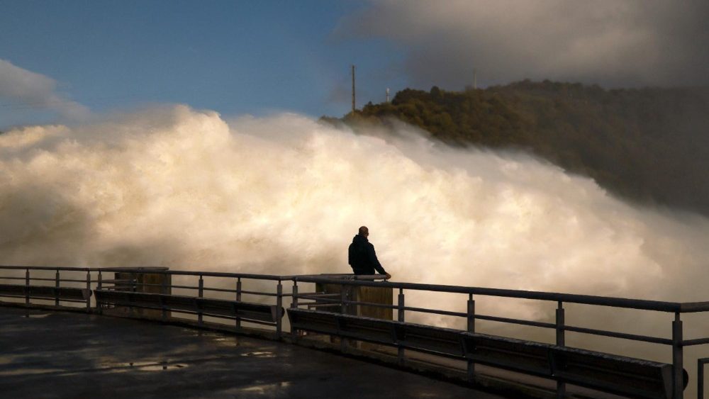 Um homem observa a barragem de Alqueva liberando água em Moura, região do Alentejo, Portugal, em 5 de fevereiro de 2026. Uma tempestade mortal que provocou inundações e milhares de evacuações na Península Ibérica gerou apelos na quinta-feira para o adiamento do segundo turno das eleições presidenciais portuguesas, mas as autoridades eleitorais insistiram que a votação ocorreria normalmente. A tempestade Leonardo desta semana deixou um morto em Portugal e atingiu a região da Andaluzia, no sul da Espanha, onde equipes de resgate buscavam uma mulher desaparecida e evacuaram milhares de pessoas. (Foto de PATRICIA DE MELO MOREIRA / AFP)