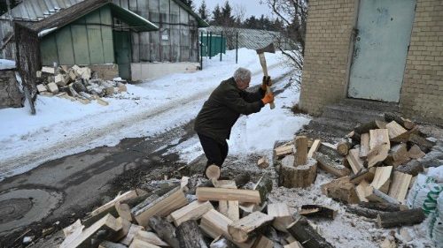 Um idoso ucraniano racha lenha na neve