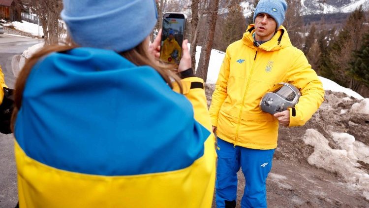 O atleta ucraniano de skeleton Vladyslav Heraskevych (&agrave; direita) segura seu capacete, que retrata v&iacute;timas da guerra de seu pa&iacute;s contra a R&uacute;ssia, em Cortina d'Ampezzo, em 12 de fevereiro de 2026. Heraskevych foi desclassificado dos Jogos Ol&iacute;mpicos de Inverno em 12 de fevereiro de 2026, ap&oacute;s se recusar a voltar atr&aacute;s em rela&ccedil;&atilde;o ao seu capacete proibido, que retrata v&iacute;timas da guerra de seu pa&iacute;s contra a R&uacute;ssia. O Comit&ecirc; Ol&iacute;mpico Internacional afirmou que ele foi expulso dos Jogos de Mil&atilde;o-Cortina "ap&oacute;s se recusar a seguir as diretrizes do COI sobre a liberdade de express&atilde;o dos atletas". (Foto de Odd ANDERSEN / AFP)