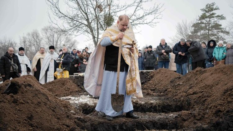 Um sacerdote ucraniano joga punhados de terra sobre os caix&otilde;es durante o funeral de Grigory Shikula, de 34 anos, seus dois filhos, Ivan e Vladislav, e sua filha, Myroslava, que foram mortos por um ataque de drone russo em um cemit&eacute;rio na vila de Skovorodynivka, na regi&atilde;o de Kharkiv, em 13 de fevereiro de 2026, em meio &agrave; invas&atilde;o russa da Ucr&acirc;nia. Um ataque de drone russo a uma casa no nordeste da Ucr&acirc;nia, em 11 de fevereiro de 2026, matou tr&ecirc;s crian&ccedil;as pequenas e seu pai, al&eacute;m de ferir a m&atilde;e gr&aacute;vida, disseram autoridades. G&ecirc;meos de um ano e uma menina de dois anos foram mortos no ataque noturno &agrave; casa da fam&iacute;lia na cidade de Bogodukhiv, a cerca de 20 quil&ocirc;metros da fronteira com a R&uacute;ssia. (Foto de Ivan SAMOILOV / AFP)