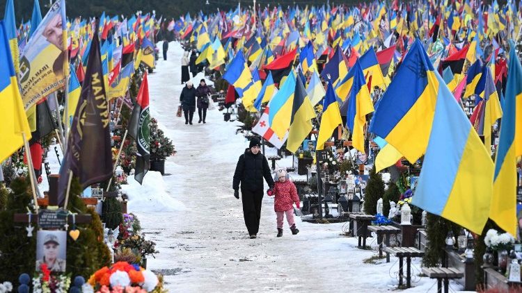 Pessoas em luto caminham no Cemit&eacute;rio Militar de Lychakiv, em Lviv, no Dia dos Namorados, em 14 de fevereiro de 2026, em meio &agrave; invas&atilde;o russa da Ucr&acirc;nia. (Foto de YURIY DYACHYSHYN / AFP)