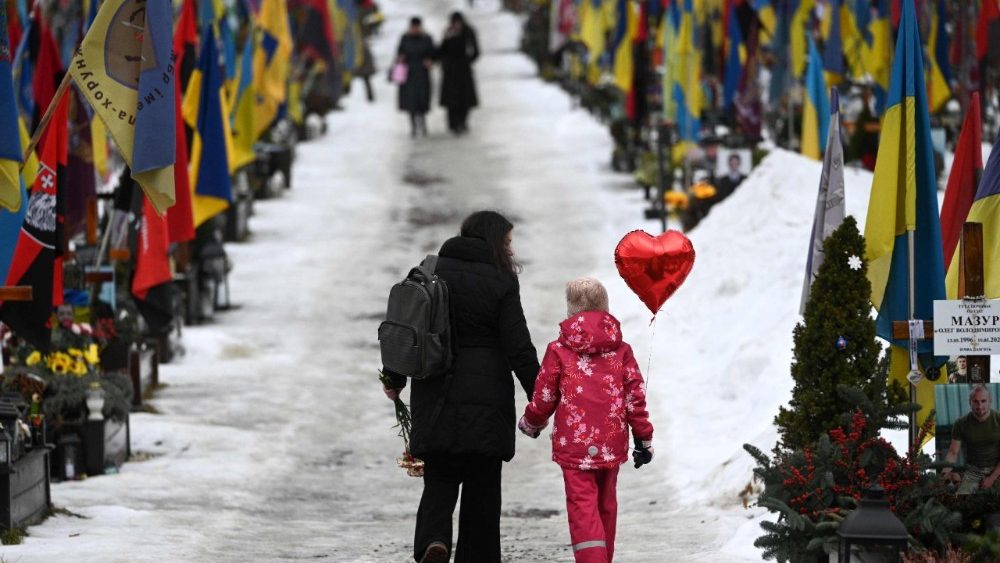 Uma mãe e sua filha caminham segurando um balão em forma de coração no Cemitério Militar de Lychakiv, em Lviv, no Dia dos Namorados, em 14 de fevereiro de 2026, em meio à invasão russa da Ucrânia. (Foto de YURIY DYACHYSHYN / AFP)   (AFP or licensors)