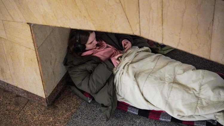 Uma garota olha para o celular enquanto se abriga em uma esta&ccedil;&atilde;o de metr&ocirc; durante um alerta de ataque a&eacute;reo, em Kiev, na madrugada de 17 de fevereiro de 2026, em meio &agrave; invas&atilde;o russa da Ucr&acirc;nia. (Foto de Serhii Okunev / AFP)