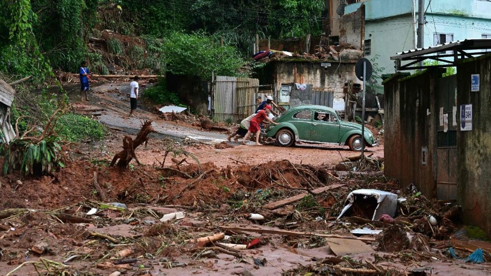 Moradores empurram um Fusca após enchentes e deslizamentos de terra no bairro de Tres Moinhos, em Juiz de Fora, Minas Gerais, Brasil, em 26 de fevereiro de 2026. (Foto de Pablo Porciúncula / AFP)