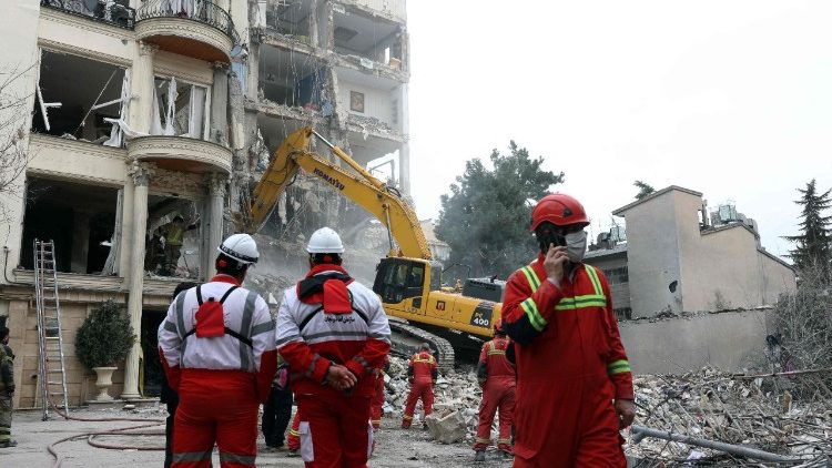 Bombeiros iranianos, com a ajuda de uma escavadeira, removem os escombros de um pr&eacute;dio residencial destru&iacute;do no norte de Teer&atilde;
