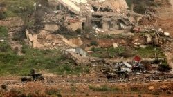Israeli military vehicles move past destroyed buildings in southern Lebanon close to the Israeli border 
