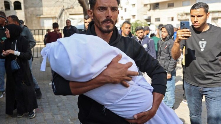 Un uomo tiene tra le braccia il corpo di una giovanissima vittima palestinese (Afp)