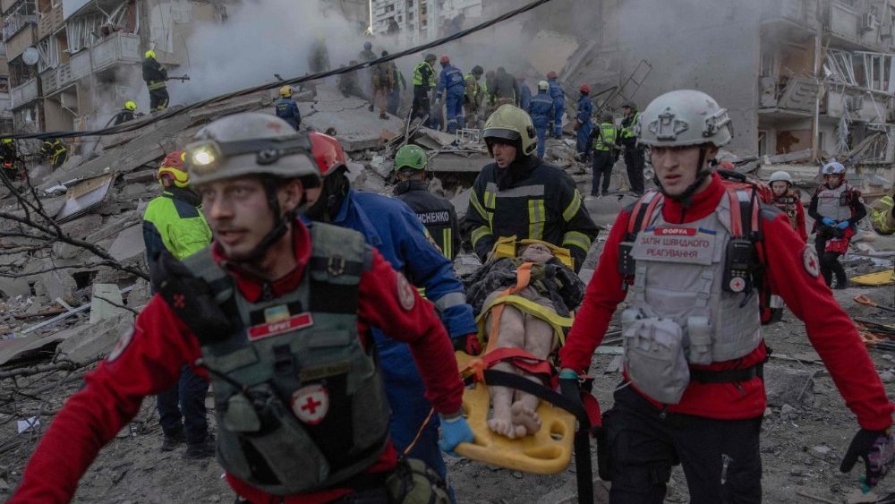 Equipes de resgate carregam uma pessoa ferida no local de um prédio residencial parcialmente destruído após ataques de drones e mísseis russos em Kiev, em 14 de maio de 2026, em meio à invasão russa da Ucrânia. A capital ucraniana sofreu intensos ataques aéreos na madrugada de 14 de maio, conforme relatado por um jornalista da AFP, enquanto o prefeito de Kiev afirmava que a Rússia estava atacando a cidade. (Foto de Roman PILIPEY / AFP) 