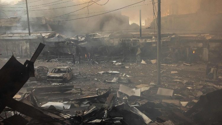 Pessoas observam a fuma&ccedil;a ao lado de carros e pr&eacute;dios incendiados ap&oacute;s ataques russos em Kiev, em 24 de maio de 2026, durante a invas&atilde;o russa da Ucr&acirc;nia. Um grande ataque com m&iacute;sseis bal&iacute;sticos atingiu Kiev na madrugada de 24 de maio, disseram as autoridades, ferindo pelo menos cinco pessoas, depois que Moscou amea&ccedil;ou retaliar pelos ataques no leste da Ucr&acirc;nia, territ&oacute;rio ocupado pela R&uacute;ssia. (Foto de Roman PILIPEY / AFP)
