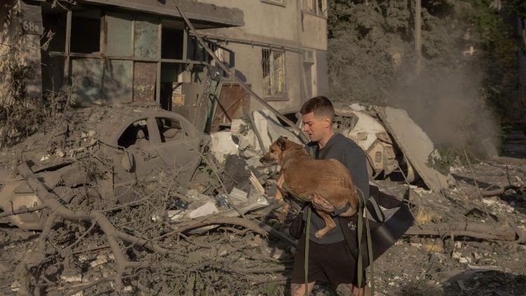 Un uomo porta in salvo il suo cane dopo i bombardamenti su Kyiv