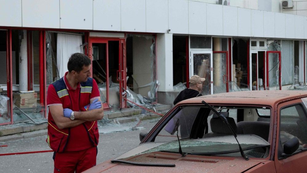 Um paramédico ucraniano está ao lado de um carro danificado em frente a um centro médico também danificado após um ataque aéreo em Kiev, em 2 de junho de 2026, durante a invasão russa da Ucrânia. A Rússia bombardeou a Ucrânia com centenas de drones e dezenas de mísseis na madrugada de 2 de junho de 2026, depois de ameaçar um ataque em larga escala e alertar cidadãos estrangeiros para que deixassem Kiev. (Foto de Serhii Okunev / AFP)