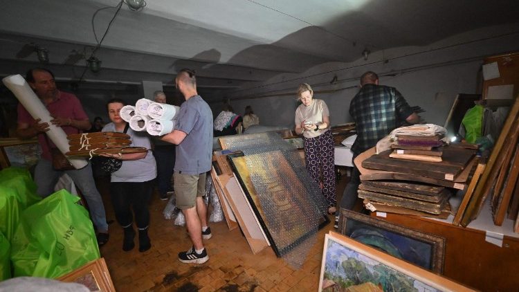 Pessoas transportam quadros para o por&atilde;o do Museu de Arte de Kharkiv, danificado por um ataque de drone em Kharkiv em 14 de junho de 2026, durante a invas&atilde;o russa da Ucr&acirc;nia. (Foto de SERGEY BOBOK / AFP)
