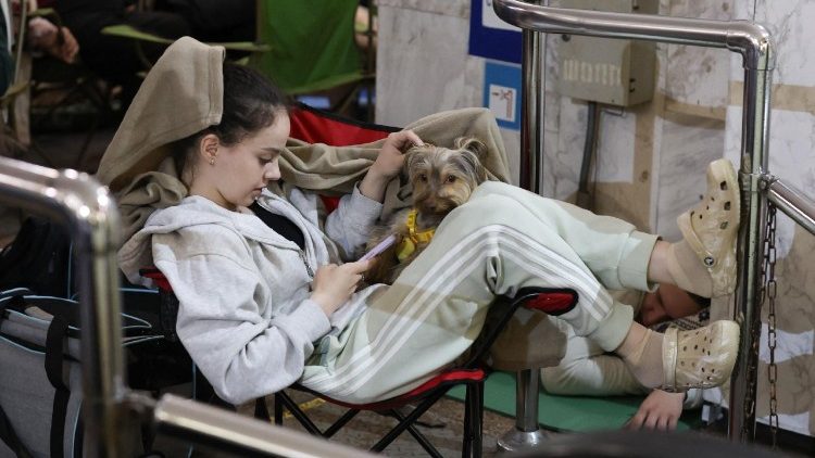 Uma pessoa se abriga com seu cachorro de estima&ccedil;&atilde;o em uma esta&ccedil;&atilde;o de metr&ocirc; durante um ataque de m&iacute;sseis russos &agrave; capital ucraniana, Kiev, em 15 de junho de 2026, em meio &agrave; invas&atilde;o russa na Ucr&acirc;nia. Um grande ataque de m&iacute;sseis atingiu Kiev na madrugada de 15 de junho, conforme testemunhado por um rep&oacute;rter da AFP, com proj&eacute;teis interceptados no c&eacute;u e destro&ccedil;os incandescentes caindo sobre a cidade. Autoridades ucranianas, incluindo o prefeito da cidade, Vitali Klitschko, relataram no Telegram que os ataques atingiram v&aacute;rios distritos. (Foto de Serhii Okunev / AFP)
