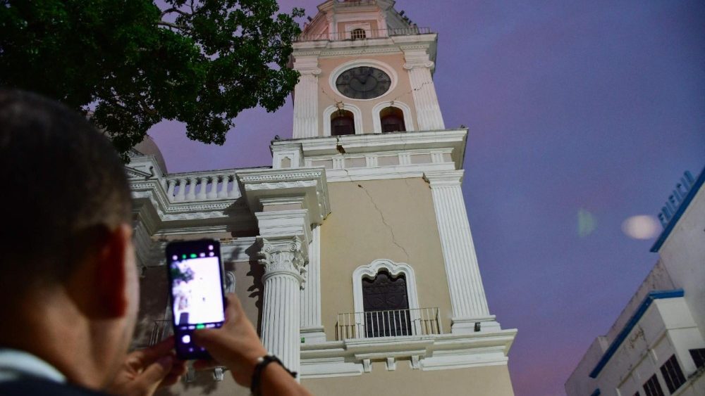 Um homem tira uma foto de uma igreja danificada após um terremoto em Valência, Venezuela, em 24 de junho de 2026. Dois terremotos de magnitude 7,2 e 7,5 atingiram a mesma área da Venezuela na noite de 24 de junho, causando o colapso de edifícios, segundo o Serviço Geológico dos Estados Unidos (USGS) e jornalistas da AFP. Os terremotos levaram os moradores da capital, Caracas, às ruas. (Foto de Jacinto OLIVEROS/AFP)