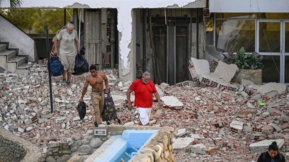 Pessoas carregam seus pertences para fora de um prédio danificado após um terremoto em Catia La Mar, estado de La Guaira, a cerca de 30 km a noroeste de Caracas, em 25 de junho de 2026.. (Foto de Federico Parra / AFP)