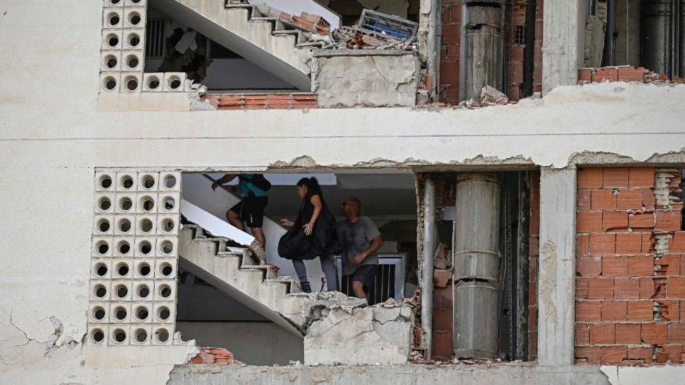 Pessoas caminham dentro de um prédio de apartamentos danificado após um terremoto em Catia La Mar, estado de La Guaira, cerca de 30 km a noroeste de Caracas, em 25 de junho de 2026. (Foto de Federico PARRA/AFP)