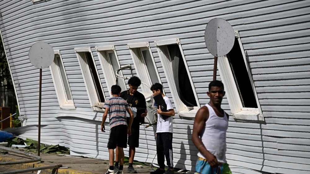  Jovens observam equipamentos de informática ao lado de um prédio residencial inclinado após um terremoto em Catia La Mar, estado de La Guaira, a cerca de 30 km a noroeste de Caracas, em 25 de junho de 2026. (Foto de Federico Parra / AFP)