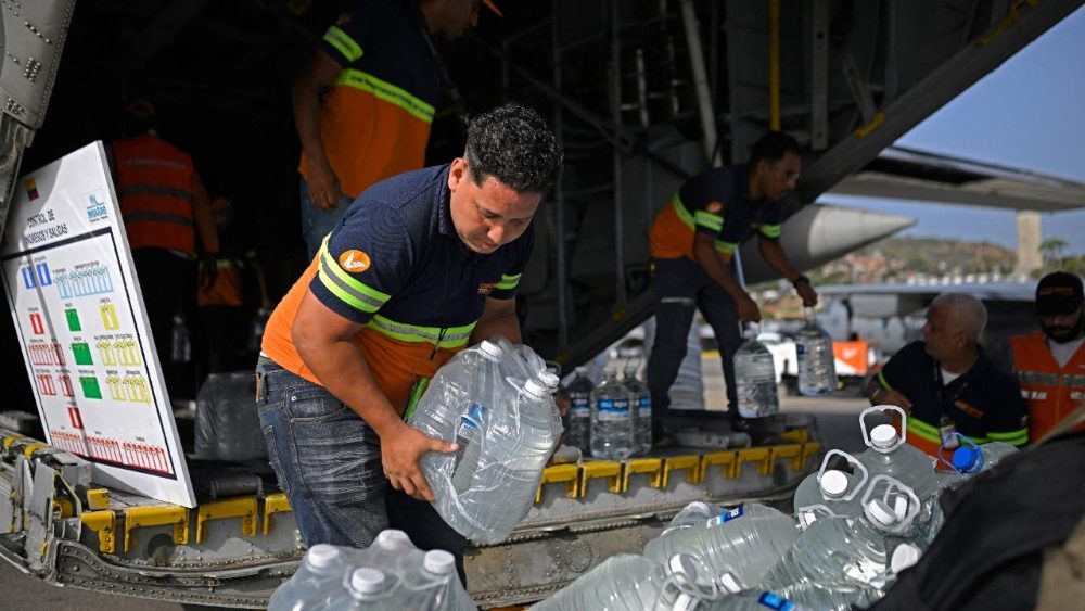 Funcionários da companhia aérea venezuelana Conviasa descarregam fardos de garrafas de água de um avião da Força Aérea Colombiana no Aeroporto Internacional Simón Bolívar, em La Guaira, Venezuela, em 26 de junho de 2026. Usando equipamentos pesados ​​ou as próprias mãos, equipes de resgate e voluntários buscavam sobreviventes do terremoto duplo na Venezuela, que deixou oficialmente 589 mortos e, segundo estimativas, milhares de desaparecidos. (Foto de Federico Parra / AFP)