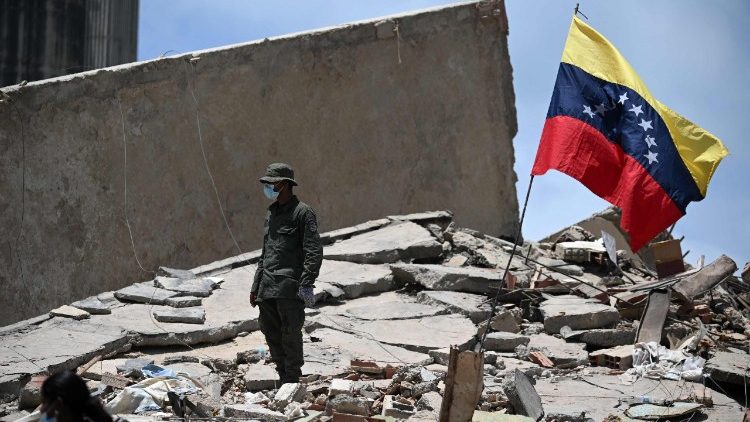 Un miembro de la Guardia Nacional Bolivariana junto a una bandera venezolana sobre los escombros de un edificio derrumbado en Caraballeda, estado de La Guaira, Venezuela