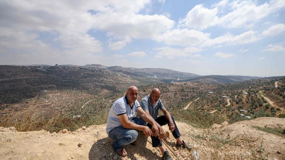 Palestinos aguardam após soldados israelenses os impedirem de retornar às suas casas e terras na vila de Qabalan, ao sul de Nablus, na Cisjordânia ocupada, em 4 de julho de 2026, depois que colonos israelenses, que haviam estabelecido um posto avançado em terras da vila, os impediram de se aproximar. (Foto de JAAFAR ASHTIYEH / AFP)