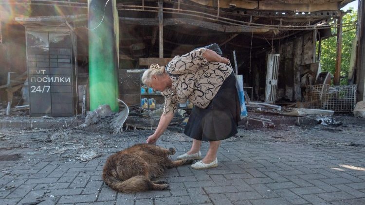 Uma mulher acaricia um cachorro perto de um posto de gasolina bastante danificado ap&oacute;s um ataque a&eacute;reo russo em Kamianske, regi&atilde;o de Dnipropetrovsk, em 7 de julho de 2026, durante a invas&atilde;o russa da Ucr&acirc;nia. (Foto de Mykola Synelnykov / AFP)