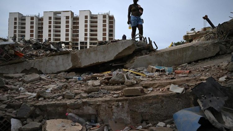 Uma mulher est&aacute; em p&eacute; sobre os escombros de um pr&eacute;dio que desabou em Caraballeda, estado de La Guaira, Venezuela, em 9 de julho de 2026, ap&oacute;s os terremotos de 24 de junho. As Na&ccedil;&otilde;es Unidas lan&ccedil;aram um apelo urgente em 8 de julho de 2026 por quase US$ 300 milh&otilde;es para as opera&ccedil;&otilde;es de socorro &agrave;s v&iacute;timas do terremoto na Venezuela, enquanto o n&uacute;mero de mortos pela trag&eacute;dia subia para mais de 3.800 pessoas. (Foto de Raul Arboleda / AFP)