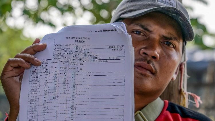 Un membro dell'equipaggio di un peschereccio mostra il contratto con la sua paga: spesso sono  retribuzioni considerate molto basse