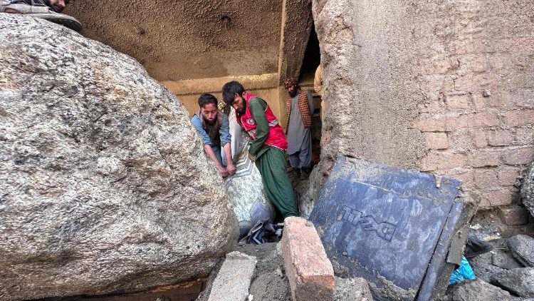 Uomini afghani perlustrano le macerie dei negozi distrutti dopo le inondazioni che hanno colpito la citt&agrave; di Parun