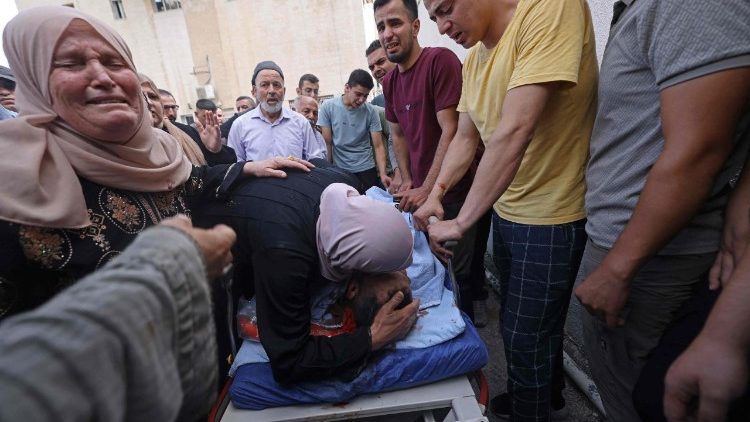 Parentes de palestinos mortos durante confrontos com colonos israelenses transportam um corpo para o hospital de Nablus .