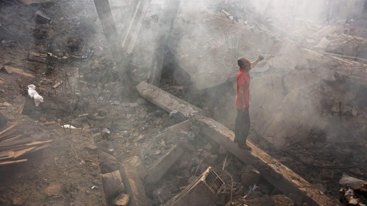 A Palestinian man looks for his belongings amid the debris after an Israeli strike in Gaza City on 24 July