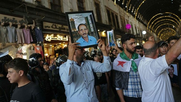 Um cidad&atilde;o s&iacute;rio carrega uma foto de um parente morto durante a guerra civil, ao final do julgamento contra o ex-presidente Assad em Damasco, em 11 de agosto