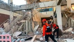 Rescue workers inspect a collapsed building in Maumere, East Nusa Tenggara, Indonesia