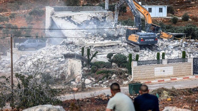 Palestinezët shikojnë buldozerët izraelitë duke shembur një ndërtesë, duke u arsyetuar për mungesën e një leje ndërtimi, në Qalandia, në jug të Ramallahut. (AFP ose licencues)