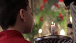 A child lights a candle at a church in Syria