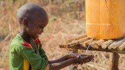 Un bambino africano prende dell'acqua da un contenitore